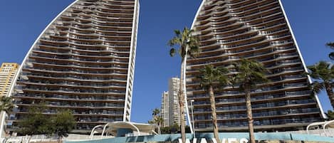 Un moderno edificio de gran altura con fachada curva, identificado como 'SUNSET WAVES'.