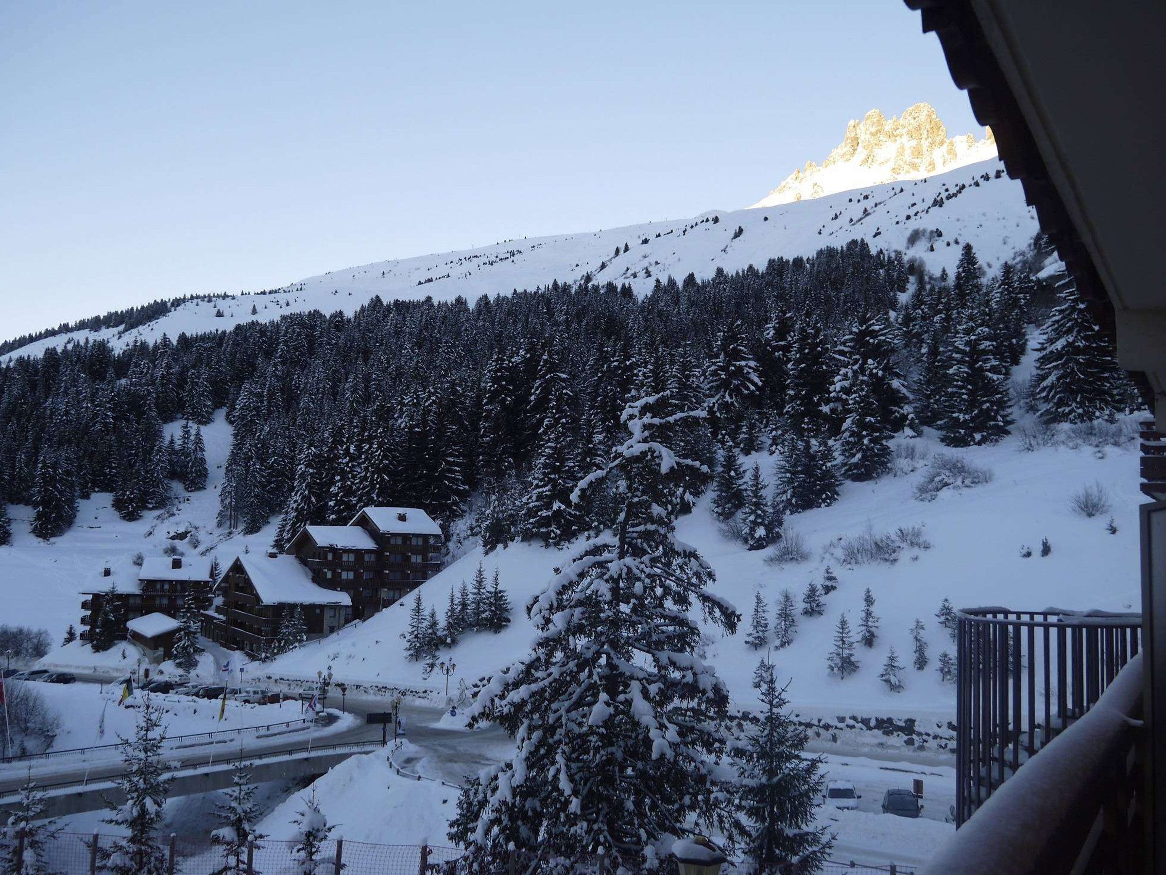 A snow-covered mountain with a lodge and a road in the foreground.