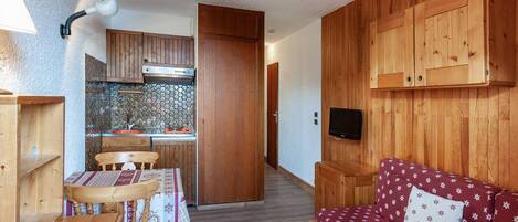 A compact living space with a kitchenette, a dining area, and a sofa.