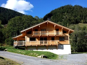 A wooden chalet with a balcony, set against a mountainous backdrop. - Spacious chalet at the foot of the slopes - 12 guests (Arêches-Beaufort)