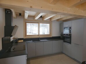 A modern kitchen with a built-in oven, a sink, and a window with a view of trees. - Spacious chalet at the foot of the slopes - 12 guests (Arêches-Beaufort)