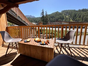 A wooden deck with a table set for two, featuring a view of a mountainous landscape. - New apartment with mountain view - 7 guests (Vars)