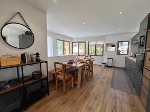 Une cuisine moderne avec un coin repas, des meubles en bois et de grandes fenêtres.