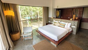 A bedroom with a large bed, a wooden headboard, a nightstand, a lamp, and a view of the outdoors.