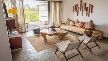Una sala de estar moderna con un sofá, dos sillones, una mesa de centro y una mesita de noche de madera.