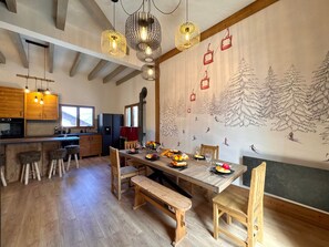 A dining area with a wooden table, benches, and a mural of a ski slope. - Spacious chalet with fireplace - 10 guests (Vars)