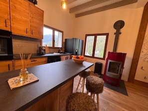 A kitchen with wooden cabinets, a central island, a red stove, and a view of mountains through the windows. - Spacious chalet with fireplace - 10 guests (Vars)