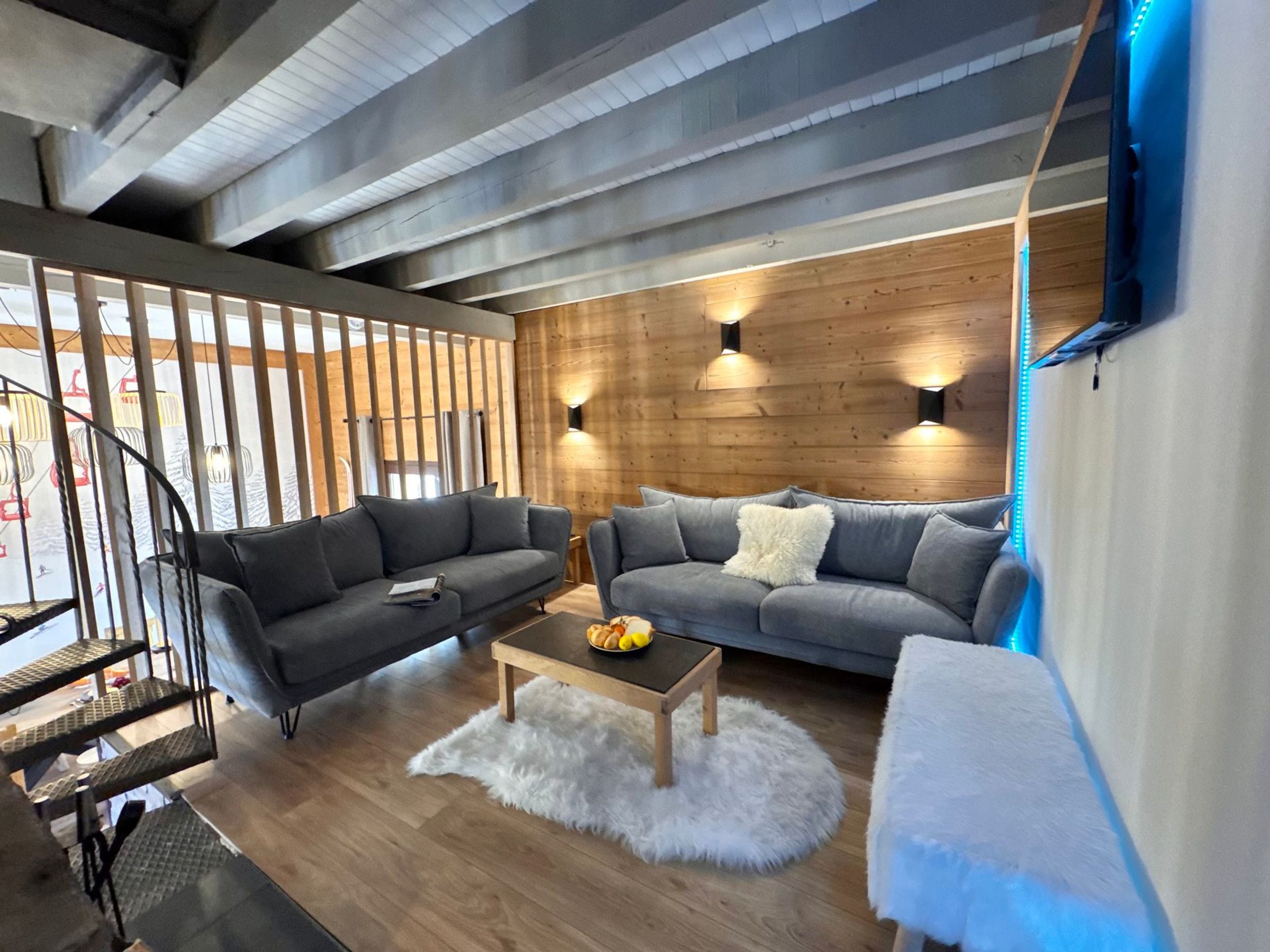 A modern living room with two sofas, a coffee table, and a staircase.