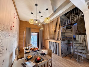 A dining area with a wooden table set for a meal, a chandelier, and a staircase with a metal railing. - Spacious chalet with fireplace - 10 guests (Vars)