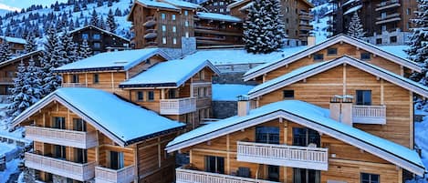 Un conjunto de cabañas de madera con balcones, rodeadas de árboles nevados y un paisaje montañoso.