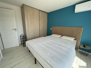 Ein Schlafzimmer mit Bett, Kleiderschrank und einem kleinen runden Tisch mit Fernbedienung.