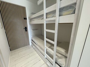 A bunk bed with a wooden slat door, a white wall, and a wooden floor. - Quiet apartment with parking - 4 guests (La Grande-Motte)