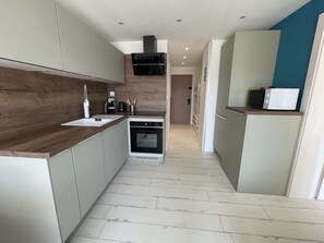 Una cocina moderna con encimera de madera, horno integrado y microondas en la encimera.