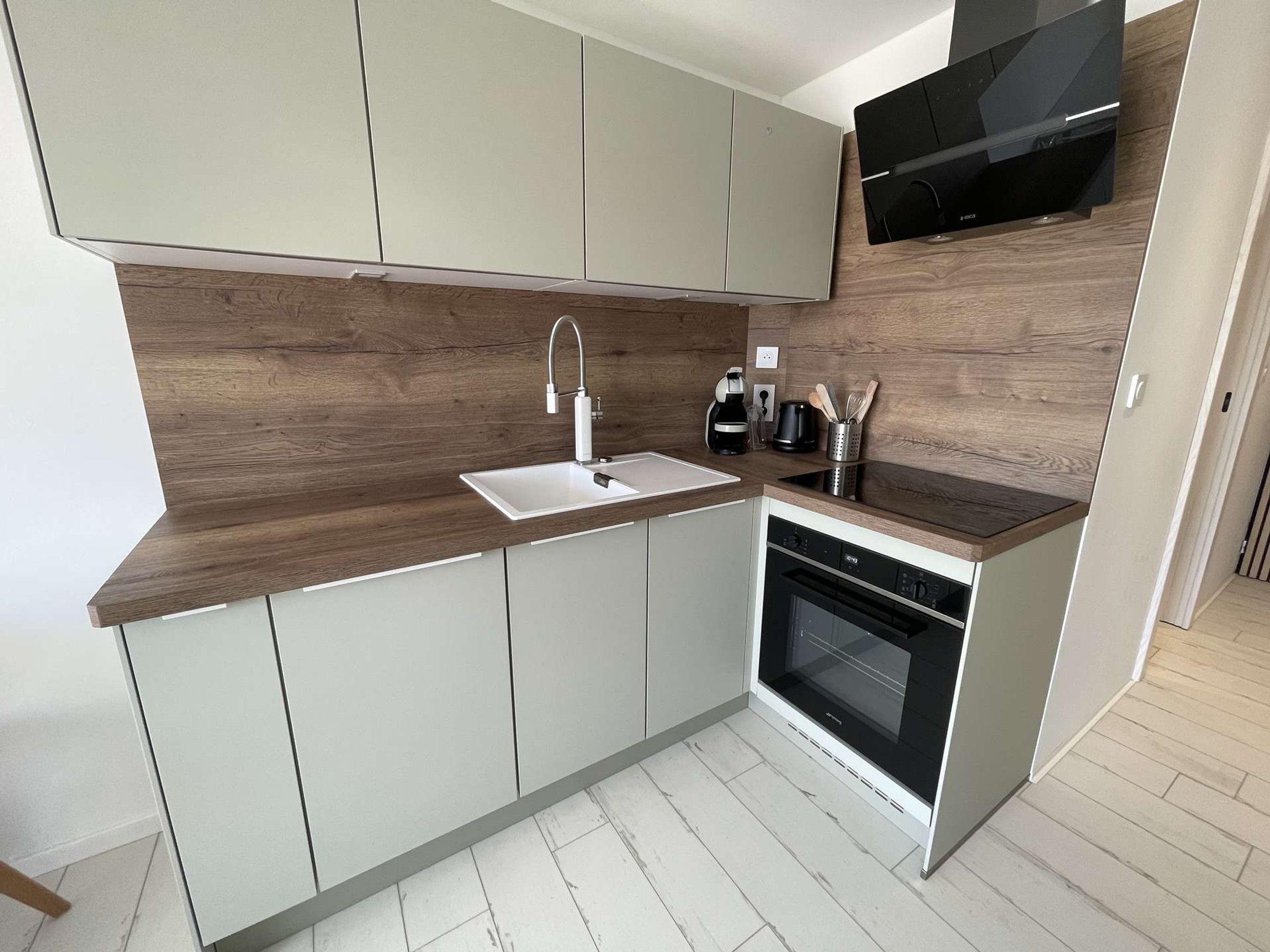 Een moderne keuken met een inbouwoven, een magnetron en een spoelbak.