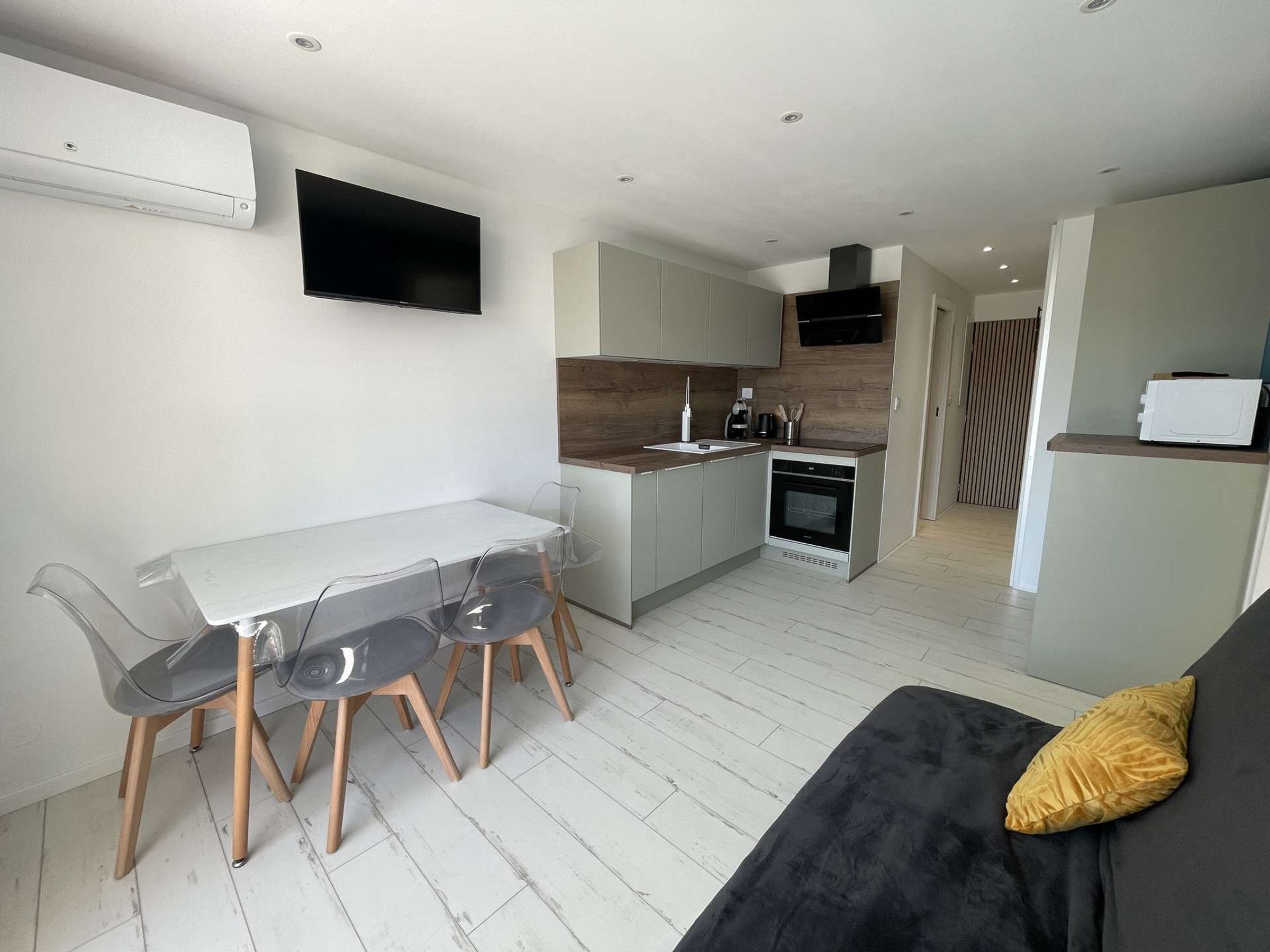 Cocina moderna con comedor, horno empotrado y televisor de pantalla plana montado en la pared.