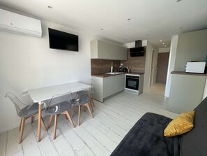 A modern kitchen with a dining area, a built-in oven, and a flat-screen TV mounted on the wall. - Quiet apartment with parking - 4 guests (La Grande-Motte)