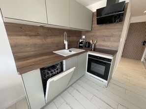 Eine kompakte Küche mit Geschirrspüler, Backofen und integriertem Mikrowellenherd.