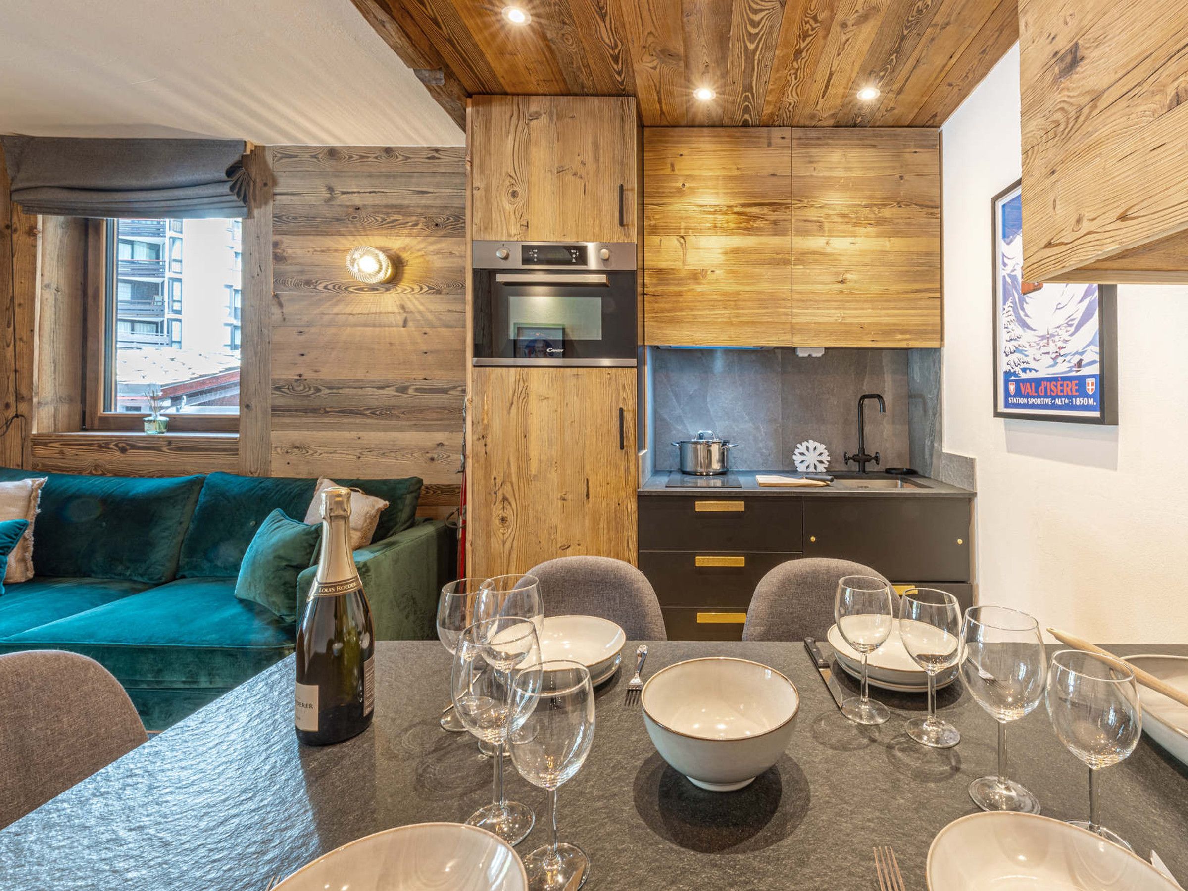A modern kitchen with wooden cabinetry, a built-in oven, and a dining area with a table set for a meal.