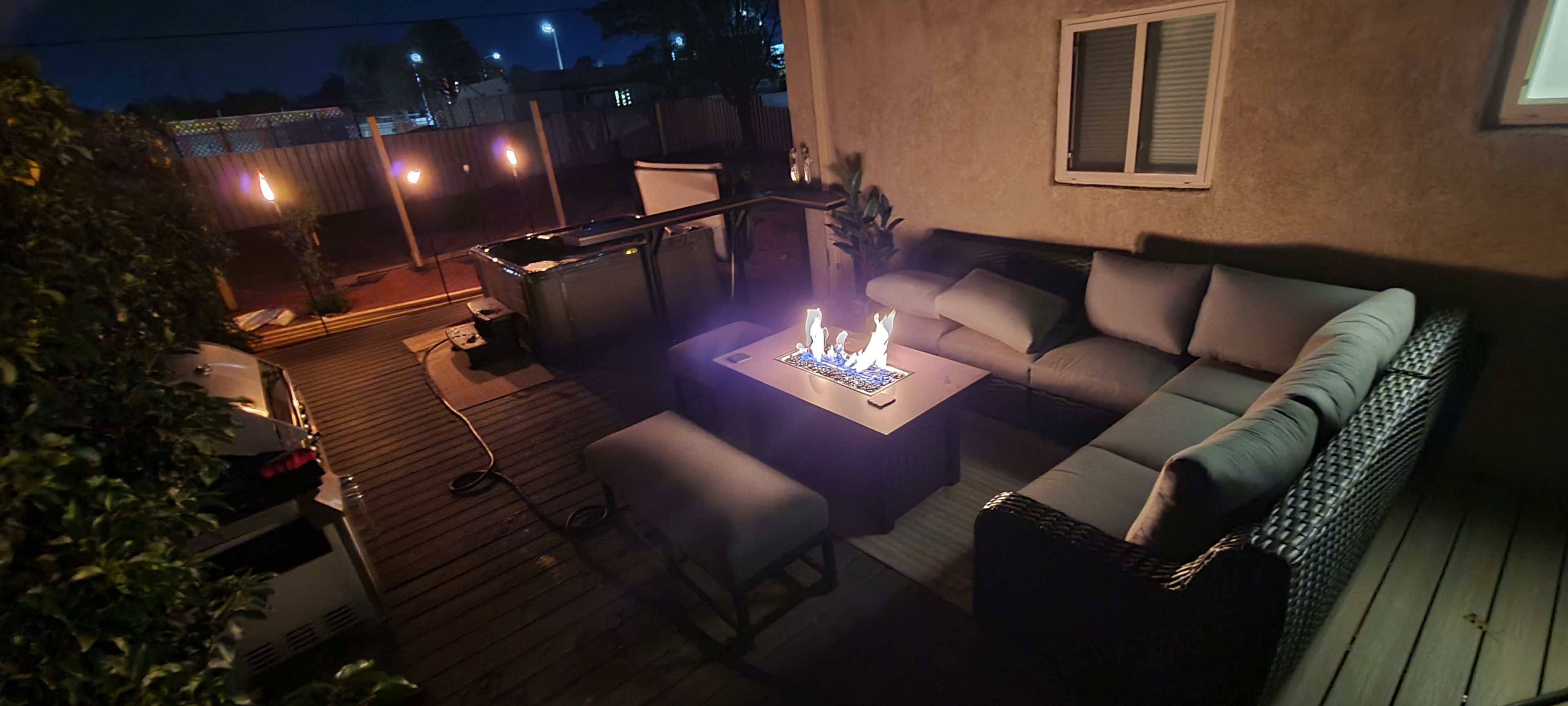 Une terrasse extérieure avec un canapé, une table et un barbecue.
