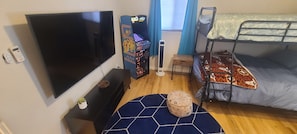 Ein Zimmer mit Fernseher, Etagenbetten, einer Musikanlage und einem kleinen Tisch mit einer Pflanze.