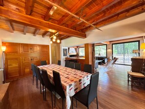 A dining area with a wooden ceiling, a table with a patterned tablecloth, and chairs.