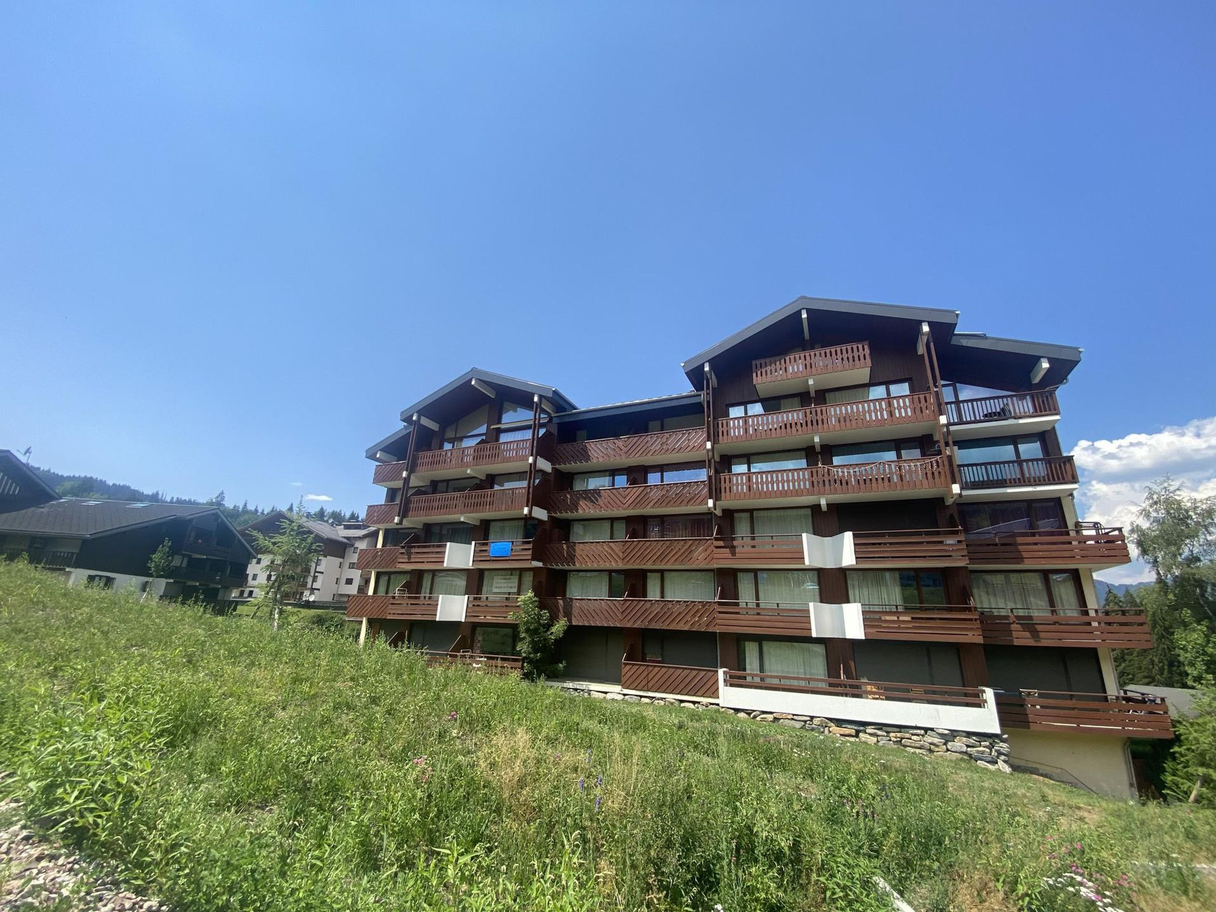 Un immeuble à plusieurs étages, doté de balcons, situé sur une colline sous un ciel dégagé.