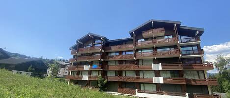 Un immeuble à plusieurs étages, doté de balcons, situé sur une colline sous un ciel dégagé.