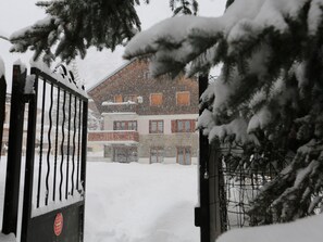Un edificio cubierto de nieve con una entrada porticada, rodeado de árboles.
