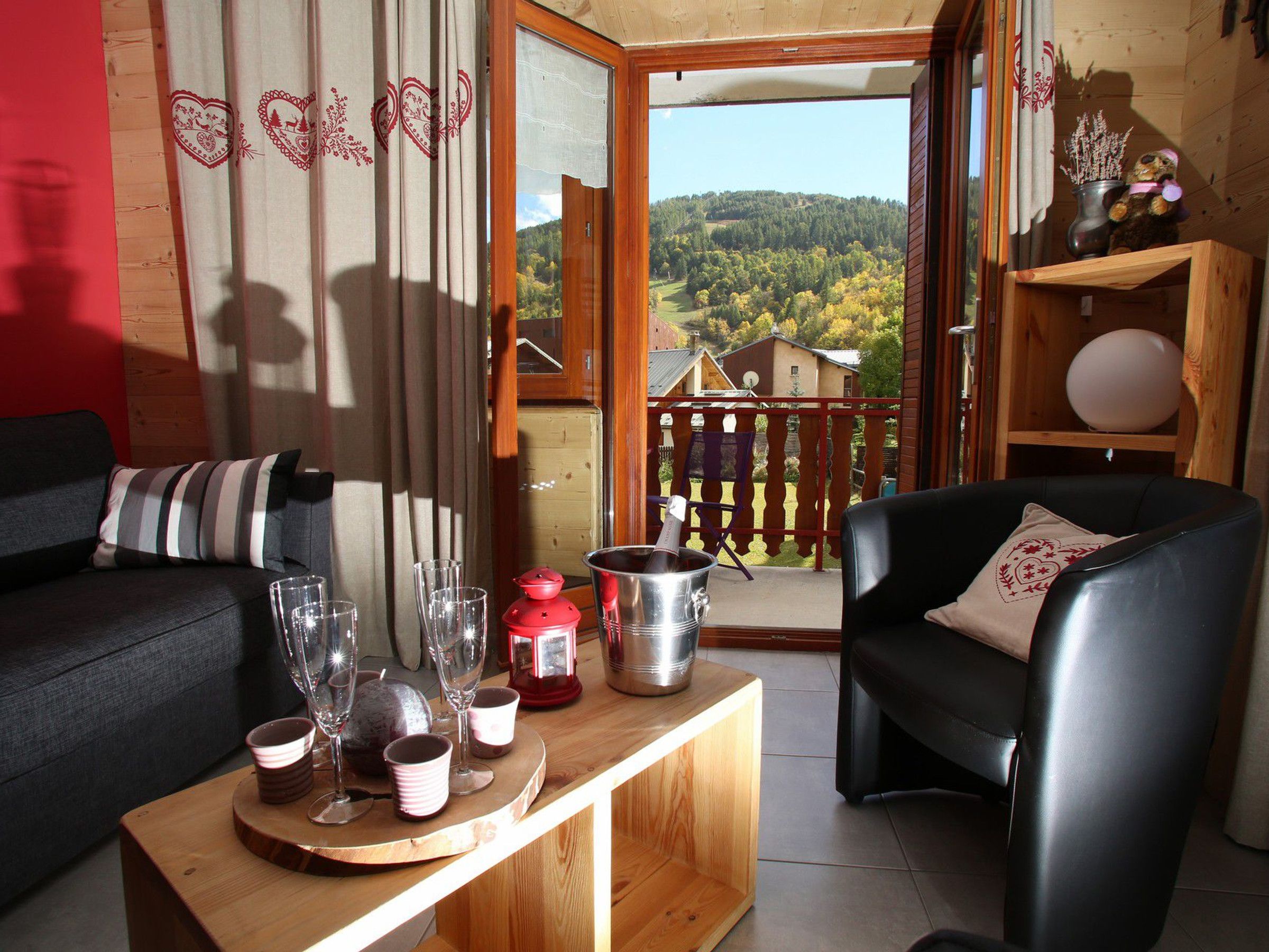 A cozy living room with a wooden coffee table, two sofas, and a balcony with a view of a forested hill.