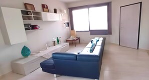 Un saló modern amb un sofà blau, una taula de consol blanca i una finestra gran.