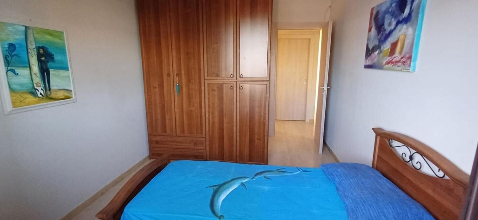 Ein Schlafzimmer mit einem Bett, einem Holzschrank und einer Tür zu einem anderen Raum.