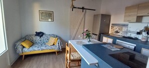 Un ambiente compatto con divano, tavolo da pranzo e angolo cottura.