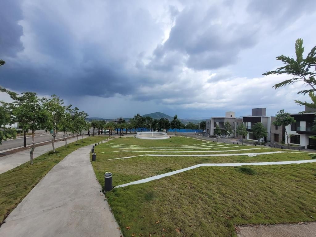 A landscaped area with a pathway, grass, and modern buildings.