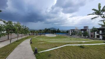A landscaped area with a pathway, grass, and modern buildings.