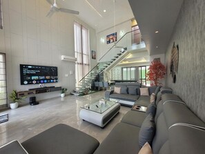 Ett rymligt vardagsrum med en modern soffgrupp, ett soffbord i glas och en platt-TV som är monterad på väggen.