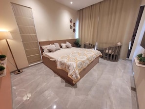 Une chambre à coucher moderne avec un grand lit, un bureau et une chaise.