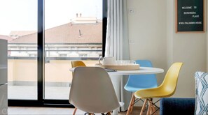 Ein modernes Zimmer mit Balkon, einem runden Tisch mit Stühlen und einem Schild an der Wand.