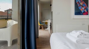 Ein Hotelzimmer mit Bett, einem Badezimmer mit weißem Stuhl, einem Schreibtisch mit Stuhl und Blick auf die Stadt.