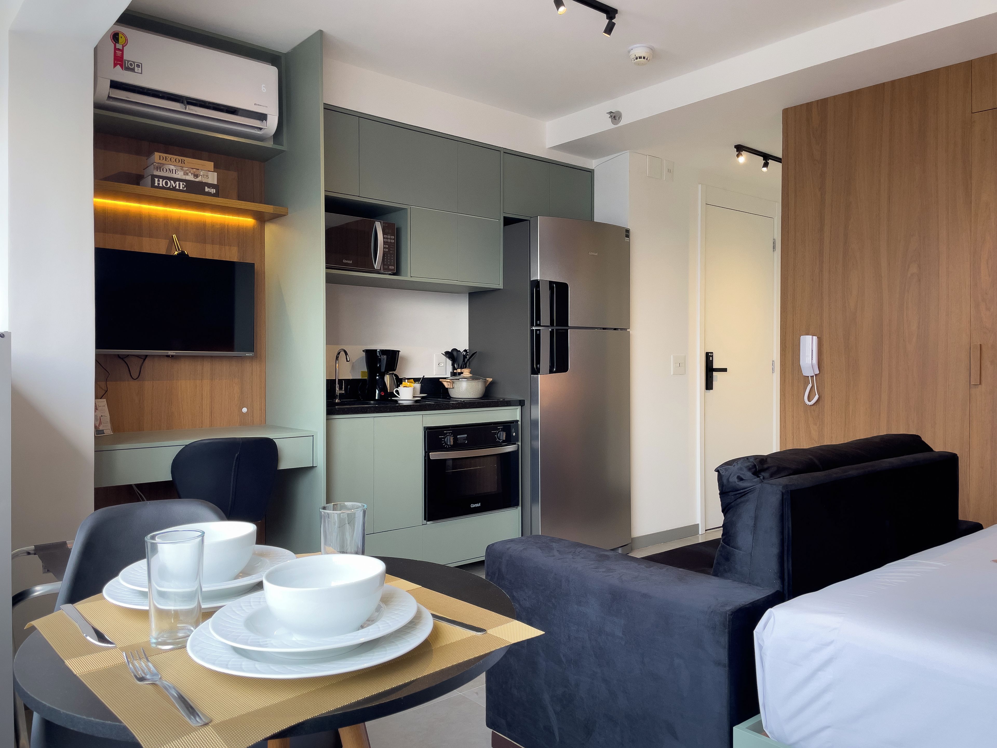Ein modernes Hotelzimmer mit Essbereich, Küchenzeile und einem Bett.