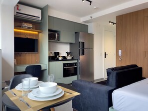Een moderne hotelkamer met een eethoek, kitchenette en een bed.