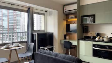 A modern kitchenette with a flat-screen TV, microwave, and coffee maker.