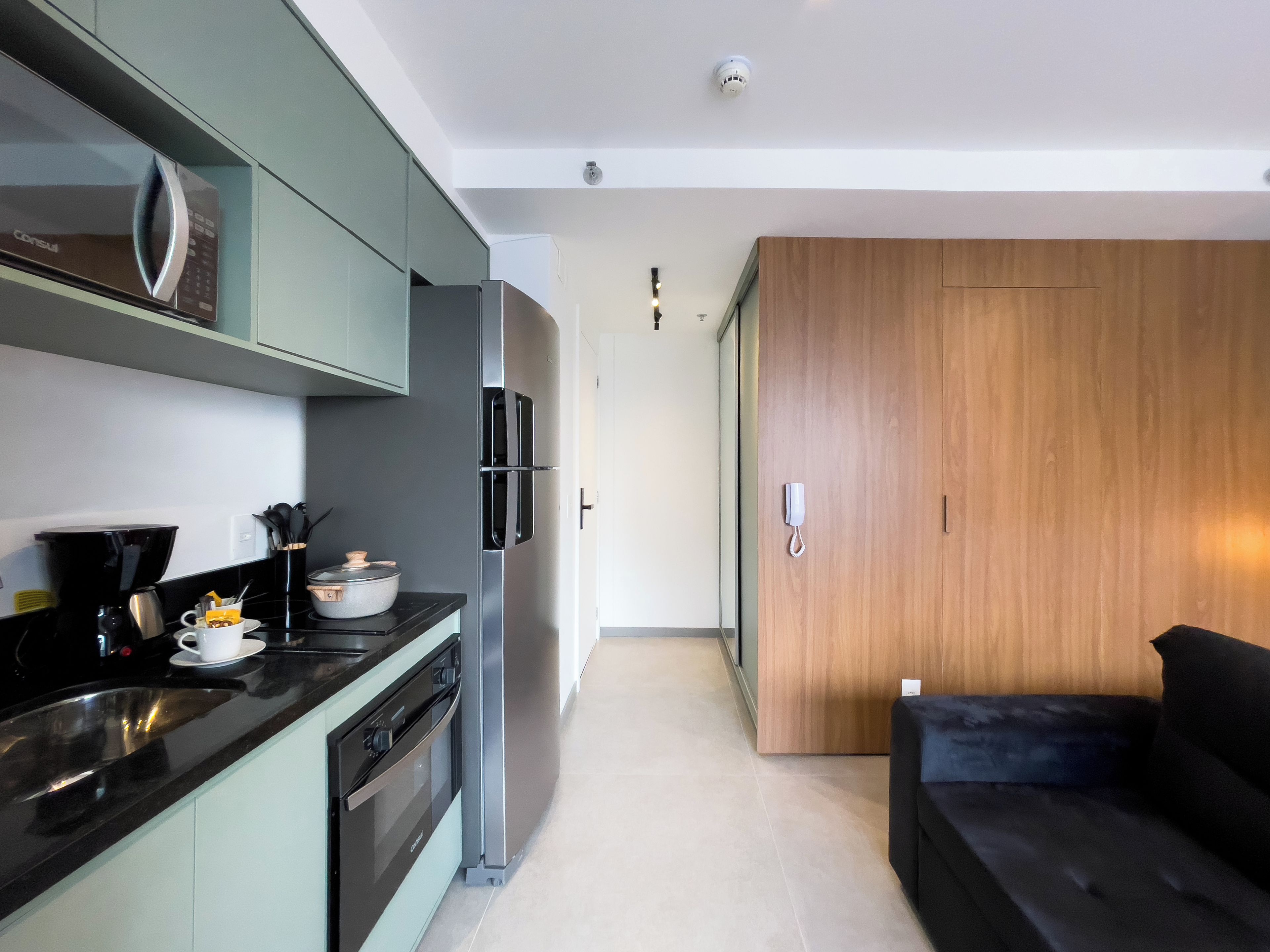 A modern kitchen with a built-in oven, a coffee maker, and a refrigerator.