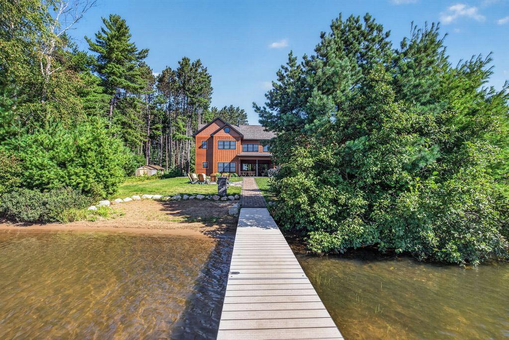 A wooden dock leading to a house surrounded by dense forest.