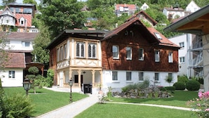 Un bâtiment traditionnel doté d’une entrée centrale, d’un jardin avec un chemin dallé et entouré d’immeubles résidentiels.
