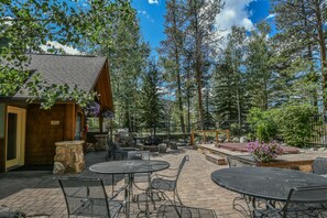 An outdoor patio with tables and chairs, surrounded by trees and a wooden structure. - NEW | Updated | Forest Views | Free Shuttle (Keystone)