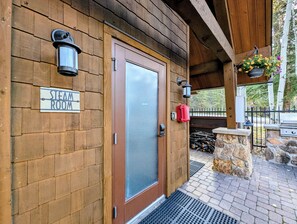 A wooden exterior with a sign reading 'STEAM ROOM,' a door, a lantern, and a stone structure with logs. - NEW | Updated | Forest Views | Free Shuttle (Keystone)