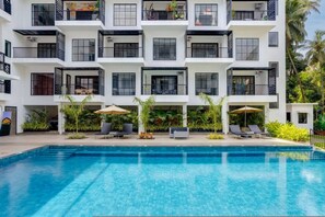 Ein mehrstöckiges Hotel mit Schwimmbad, Außenbereich und Balkonen.