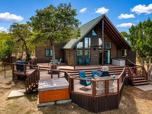 A wooden cabin with a deck, outdoor seating, and a hot tub. - Emberwood | Hot Tub, 2 Fireplaces, Sleeps 9 (Heber)