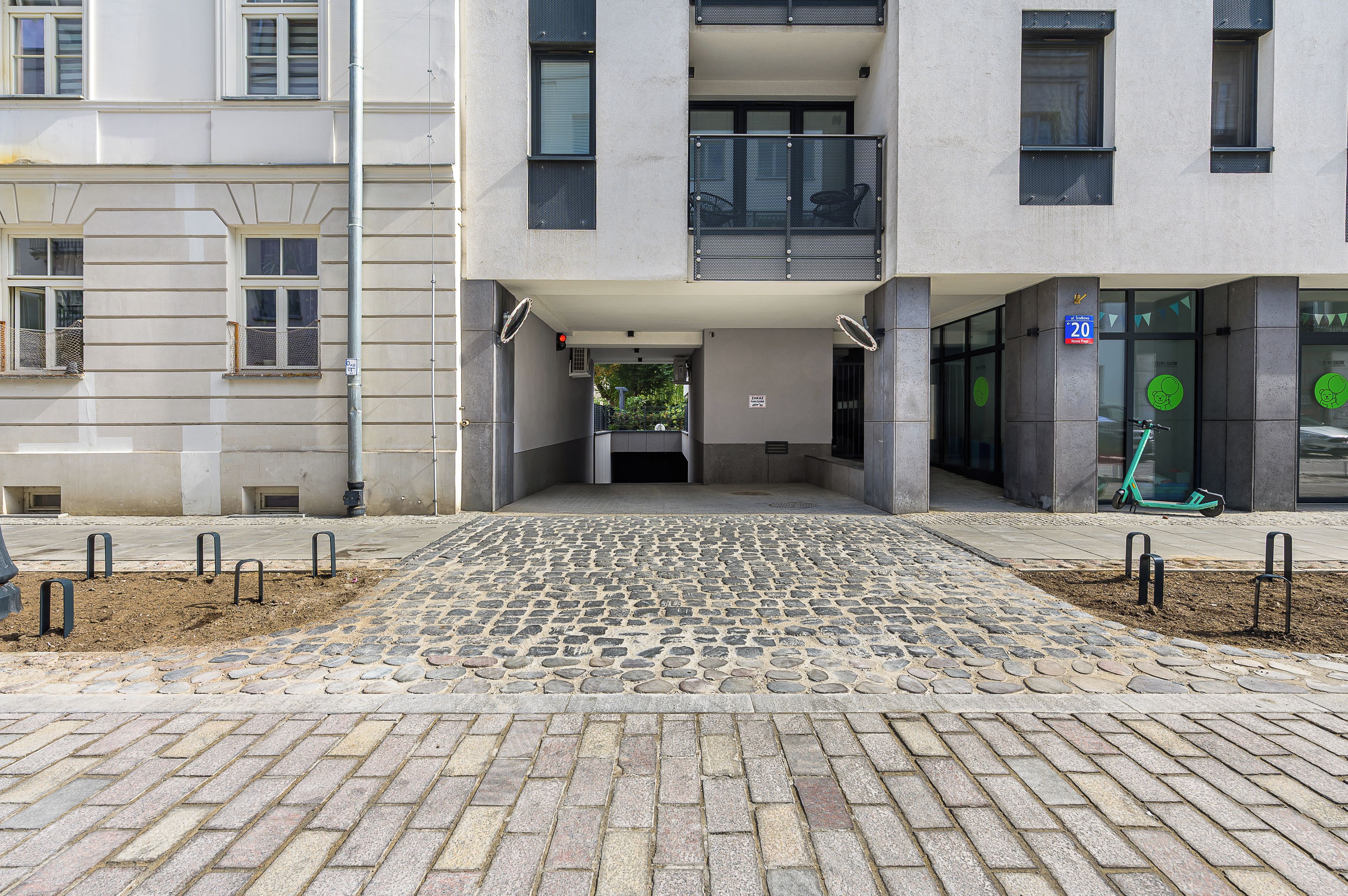 Une entrée d’immeuble avec un chemin pavé menant à une porte d’entrée.