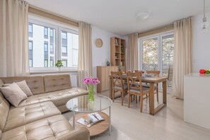 A modern living room with a leather sofa, a glass coffee table, and a dining area with wooden chairs and a table. - Lumina 4-room Apart, Parking, Balcony (Warszawa)
